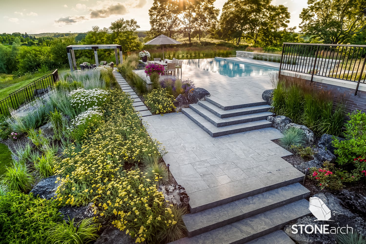 Comprehensive landscape design with natural stone pavers, steps, and copings in a luxury GTA backyard